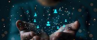 Hands holding glowing network of connected human icons, symbolizing digital social connections and global networking concept against dark background.