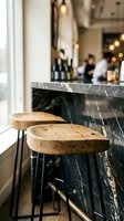 Modern bar counter with wooden round seat tops and black marble surface, featuring blurred background of people and wine bottles for hospitality, restaurant, or cafe design use.