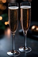Two elegant champagne flutes filled with sparkling wine against warm bokeh lights background for celebration and festive occasions.
