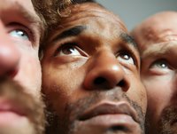 Close-up portrait of diverse men looking upward with contemplative expressions, showcasing different skin tones and facial features in dramatic lighting.