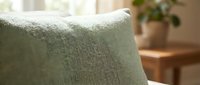 Close-up of soft sage green upholstered furniture fabric texture with natural daylight, suitable for interior design, home decor, and furniture marketing materials.