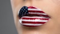 Close-up of woman's lips painted with stars and stripes flag pattern in red white and blue colors for patriotic makeup concept and national pride celebration.