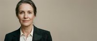 Middle-aged woman with light skin tone and shoulder-length brown hair wearing dark blazer and white shirt against neutral background for corporate and professional use.