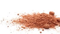 Cocoa powder and crushed cocoa nibs scattered on white background, isolated for culinary, baking, and food styling design projects.