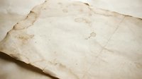 Aged parchment paper with torn edges and coffee stains creates authentic vintage texture for historical documents and antique design projects.
