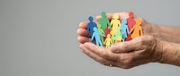 Hands holding colorful paper cutout figures representing diversity, teamwork and community support concepts for social campaigns and inclusion projects.