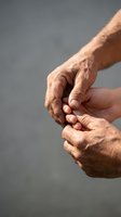 Elderly wrinkled hands holding together showing connection, support and care between generations on neutral background for healthcare concepts.