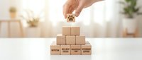 Hand placing wooden cube with star rating on pyramid of blocks labeled with customer service terms on white desk in bright office environment.