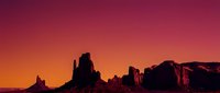 Desert rock formations silhouetted against vibrant orange and pink sunset sky, suitable for travel, nature, and landscape design projects.