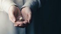 Professional businessman holding small golden compass in cupped hands symbolizing guidance, direction and leadership in corporate decision making.