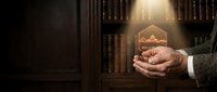 Businessman hands protecting glowing growth chart icon in elegant library office setting with warm lighting and wooden bookshelves background.
