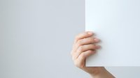 Hand holding blank white paper or card against neutral background, suitable for advertising, marketing campaigns, presentations, and promotional materials.