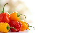Fresh colorful bell peppers and hot chili peppers arranged on white background with copy space for healthy cooking and spicy food preparation.