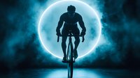Silhouette of cyclist riding bike against glowing blue moon with dramatic atmospheric clouds, suitable for sports and energy-themed designs.