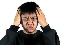 Frustrated young Asian man holding head in hands showing stress and headache on white background isolated for design use.