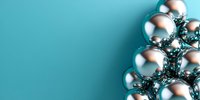 Shiny silver Christmas baubles arranged in corner composition against turquoise background with copy space, festive holiday decoration concept.