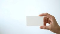 Hand holding blank white business card against light background for branding and corporate identity mockup purposes.