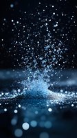 Magical explosion of glowing blue particles and water drops creating dynamic splash effect against dark background, with bokeh lights and motion blur.