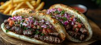 Grilled beef sandwich topped with fresh pico de gallo, purple onions and herbs on rustic wooden board served with golden french fries in dark moody setting.