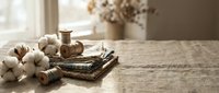 Rustic wooden spools of thread with cotton bolls and wicker basket on weathered wood table creating cozy crafting atmosphere for sewing projects.