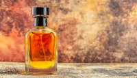 Glass bottle of golden brown whiskey on rustic wooden surface against dramatic orange and brown textured background, luxury spirits photography.