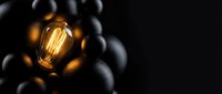 Glowing golden light bulb surrounded by dark spheres on black background, representing innovation, creativity, and unique ideas for business and technology concepts.