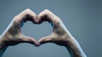 Hands forming heart shape gesture against blue sky background expressing love affection romance connection unity togetherness emotional bond relationship symbol.