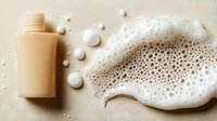 Creamy body wash bottle with rich foam bubbles and pearls on neutral background for skincare and beauty product advertising.