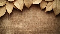 Golden autumn leaves arranged in curved border on natural burlap background with copy space, creating rustic organic composition for seasonal designs.