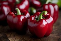 Fresh red bell peppers on rustic wooden surface for healthy cooking and meal preparation in kitchen settings.