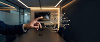 Businessman in dark suit touching glowing digital circuit board interface with data streams in modern office workspace, representing technology innovation and digital transformation.