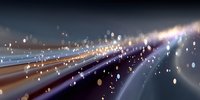 Abstract light trails and bokeh effect creating a dynamic motion blur on dark background, suggesting speed, technology, and urban nightlife.