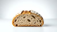 Artisan sourdough bread slice showing airy crumb structure with large holes, golden crust and rustic texture on white background for food photography.