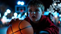 Young boy in red hoodie holding basketball at night with dramatic blue bokeh lights creating atmospheric sports portrait. Determination and dreams concept.
