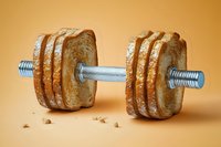 Creative dumbbell made from sliced bread loaf with metal bar through center on orange background, concept of diet and fitness balance.