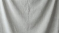 Natural linen fabric texture with soft folds and wrinkles in neutral beige color for interior design and textile backgrounds.