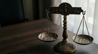 Vintage brass scales of justice on wooden desk symbolizing law, legal system, fairness and judicial balance in courtroom or law office setting.