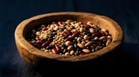 Mixed legumes and beans in rustic wooden bowl on dark background for healthy cooking and nutrition concepts.