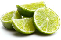 Fresh lime wedges and slices arranged on white background showing juicy citrus fruit pulp and green peel, isolated for food and beverage photography.