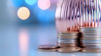 Stacked coins with metal spring coil on blurred bokeh background representing financial growth, savings, investment planning and economic stability concepts.