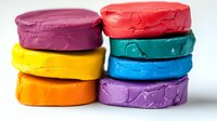 Colorful stacked modeling clay or play dough circles showing texture and layers in vibrant rainbow colors against white background, isolated craft material.