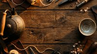 Vintage tea ceremony setup with cast iron teapot, cups, and dried herbs on rustic wooden surface. Flat lay composition for beverage, wellness, and lifestyle content.