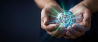 Hands holding glowing shield symbol representing cybersecurity, data protection, and digital safety for technology and business concepts.