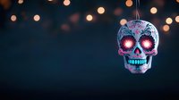 Mexican sugar skull decoration with glowing pink eyes against dark background with blurred festive bokeh lights, celebrating Day of the Dead tradition.