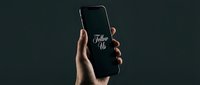 Hand holding a smartphone with Follow Us text on screen against dark background, social media marketing concept.