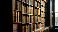 Vintage library interior with wooden bookshelves filled with old leather-bound books creating warm academic atmosphere for educational content.