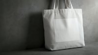 Blank white cotton tote bag with handles on gray concrete surface, ready for branding, mockup, or retail packaging design projects.