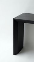 Modern black minimalist desk or table corner detail on white background for contemporary office and home interior design projects.