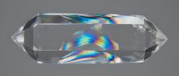 Clear quartz crystal with rainbow light refraction displaying prismatic colors on gray background for healing and meditation practices.