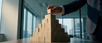 Businessman in suit stacking wooden blocks in pyramid formation, representing growth, strategy, and risk management in corporate environment.